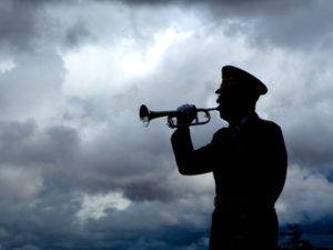 Silhouette of a man playing taps on his bugle at a veterans funeral at Medical Lake Veterans Memorial in Washington.